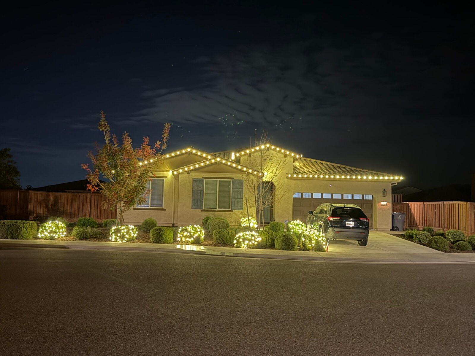 Christmas light installers in Folsom, CA: single story stucco warm white roofline lit shrubs
